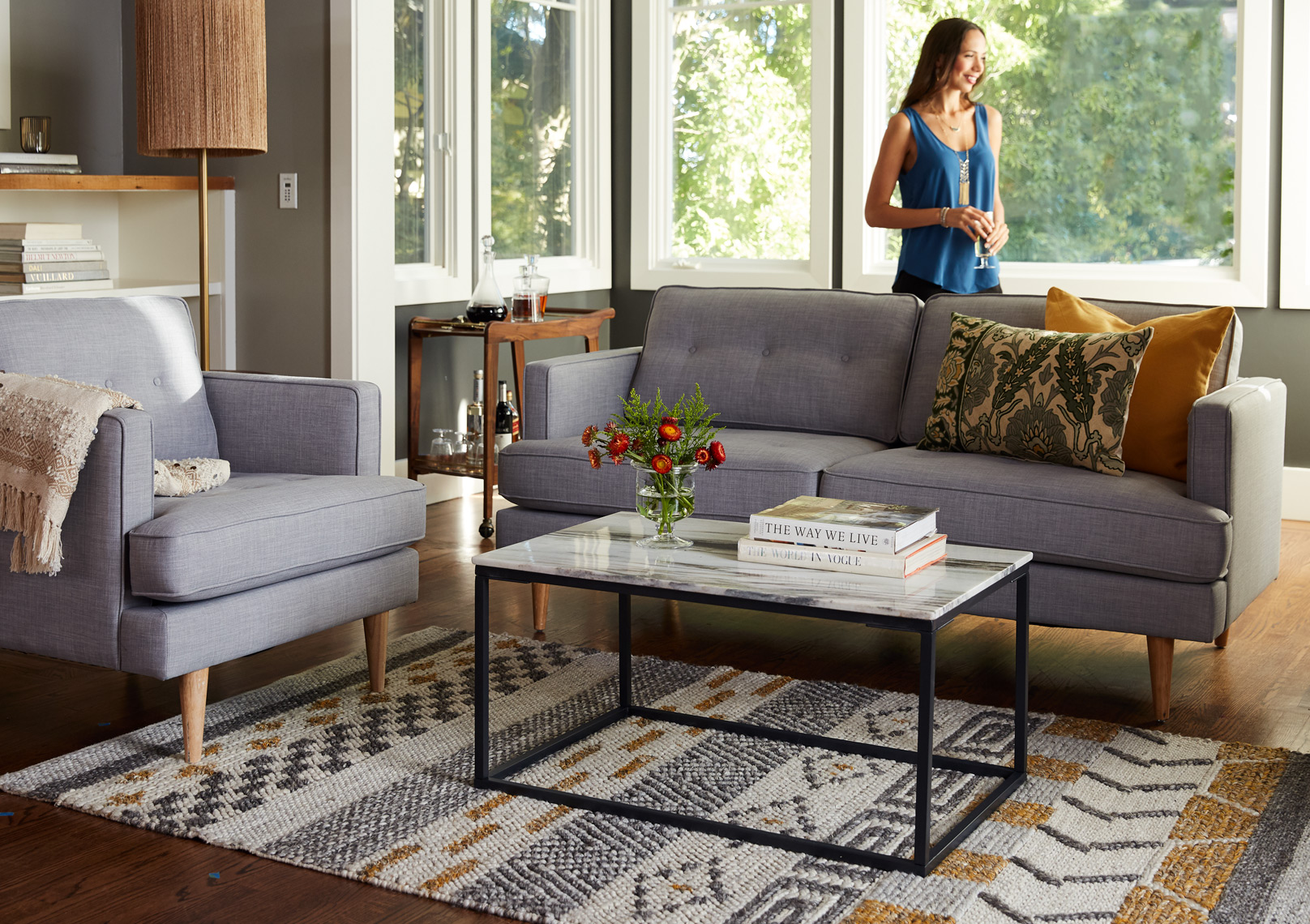 Living room grey upholstered furniture patterned rug in front of windows 