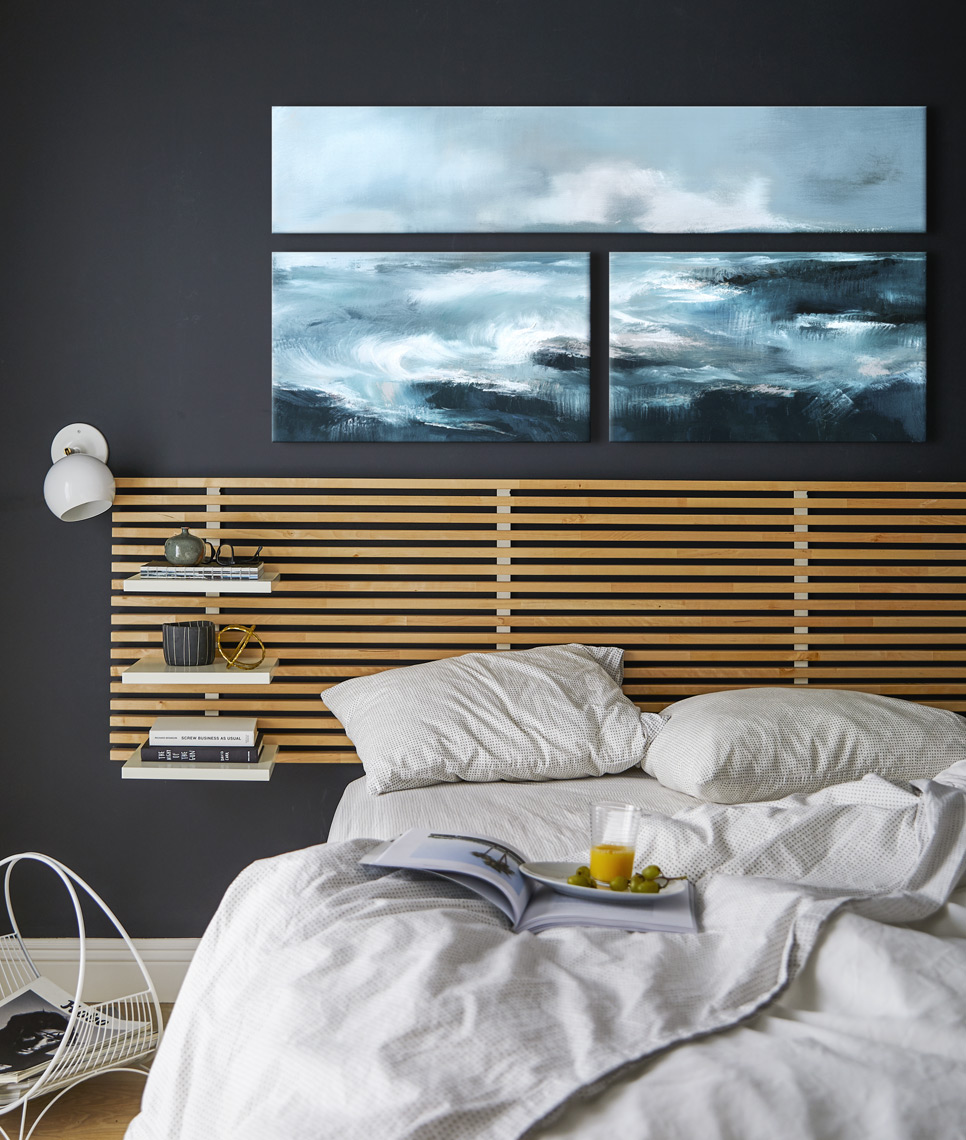 Bedroom with dark wall modern headboard messy bed white sheets under triptych painting on canvas Sean Dagen Photography