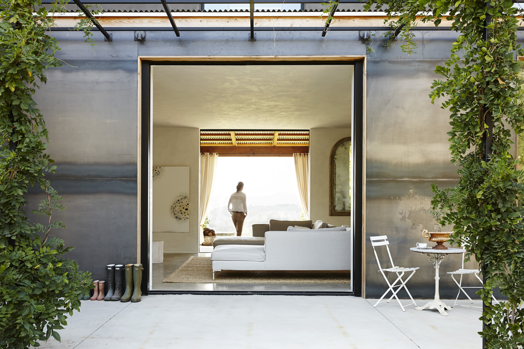 Exterior of modern house in Napa Valley with steel walls vines and woman walking through room Sean Dagen Photography