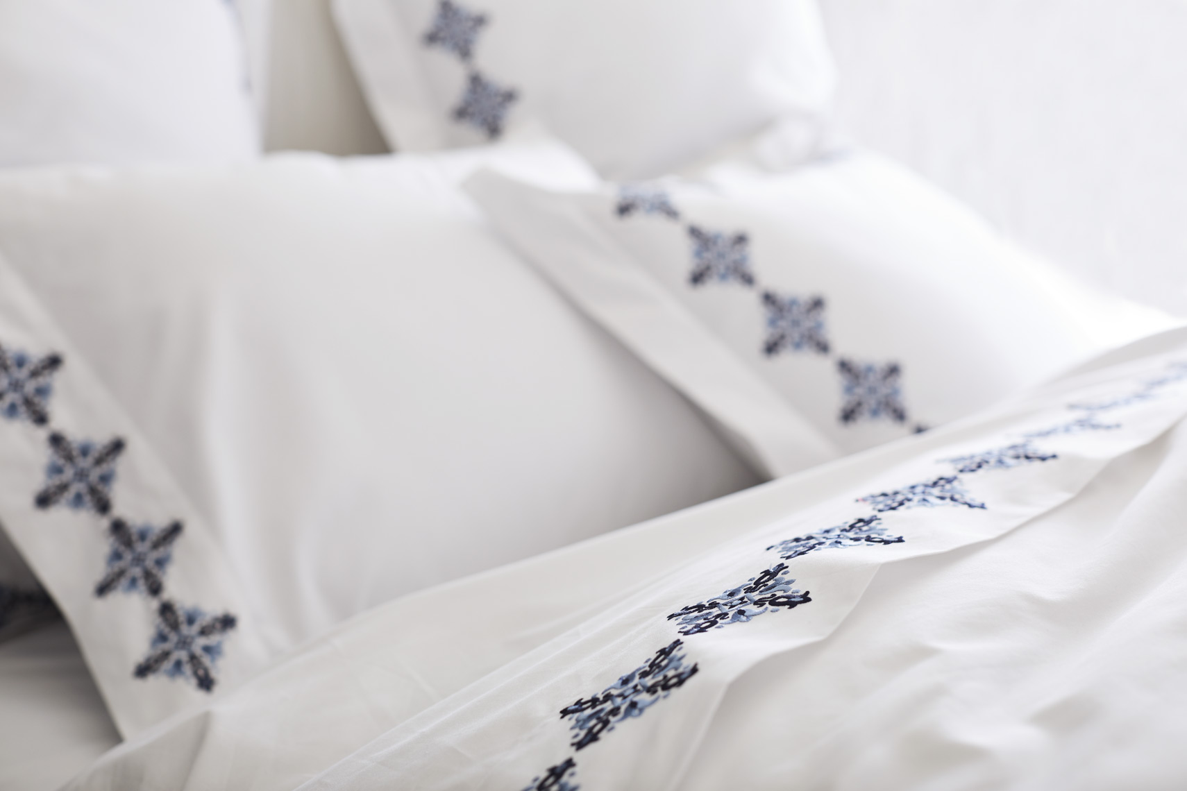 White pillows with blue pattern border on white bedding